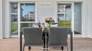 Un espace de restauration en plein air avec une table dressée pour deux personnes, un vase rempli de fleurs et une vue sur le quartier.