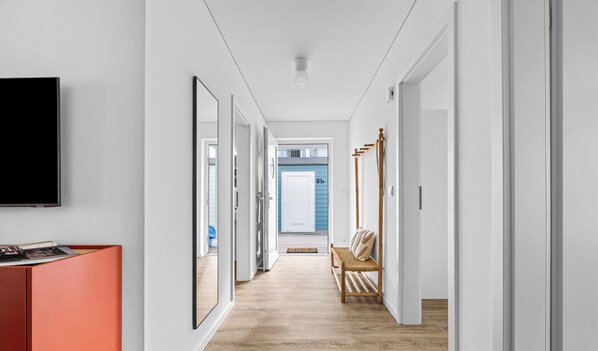 A hallway with a television, a bench, and a door leading to a room. - Sprotte 1 - Terrace, Infrared Sauna, and Fireplace, Close to the Beach (Olpenitz)