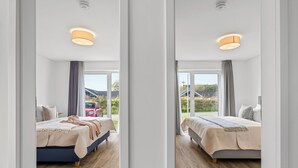 Une chambre d’hôtel moderne avec deux lits, un plancher en bois et de grandes fenêtres donnant sur l’extérieur.