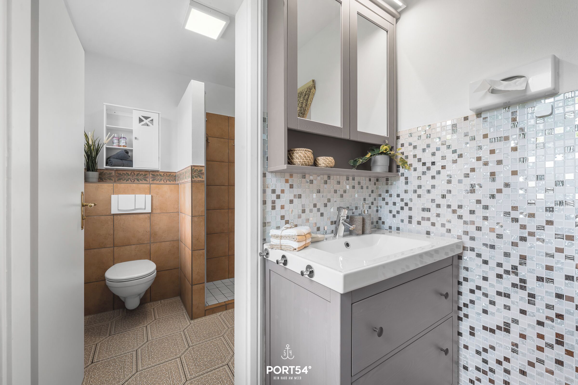 Un baño moderno con inodoro, lavamanos y espejo.