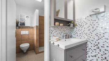 Un baño moderno con inodoro, lavamanos y espejo.