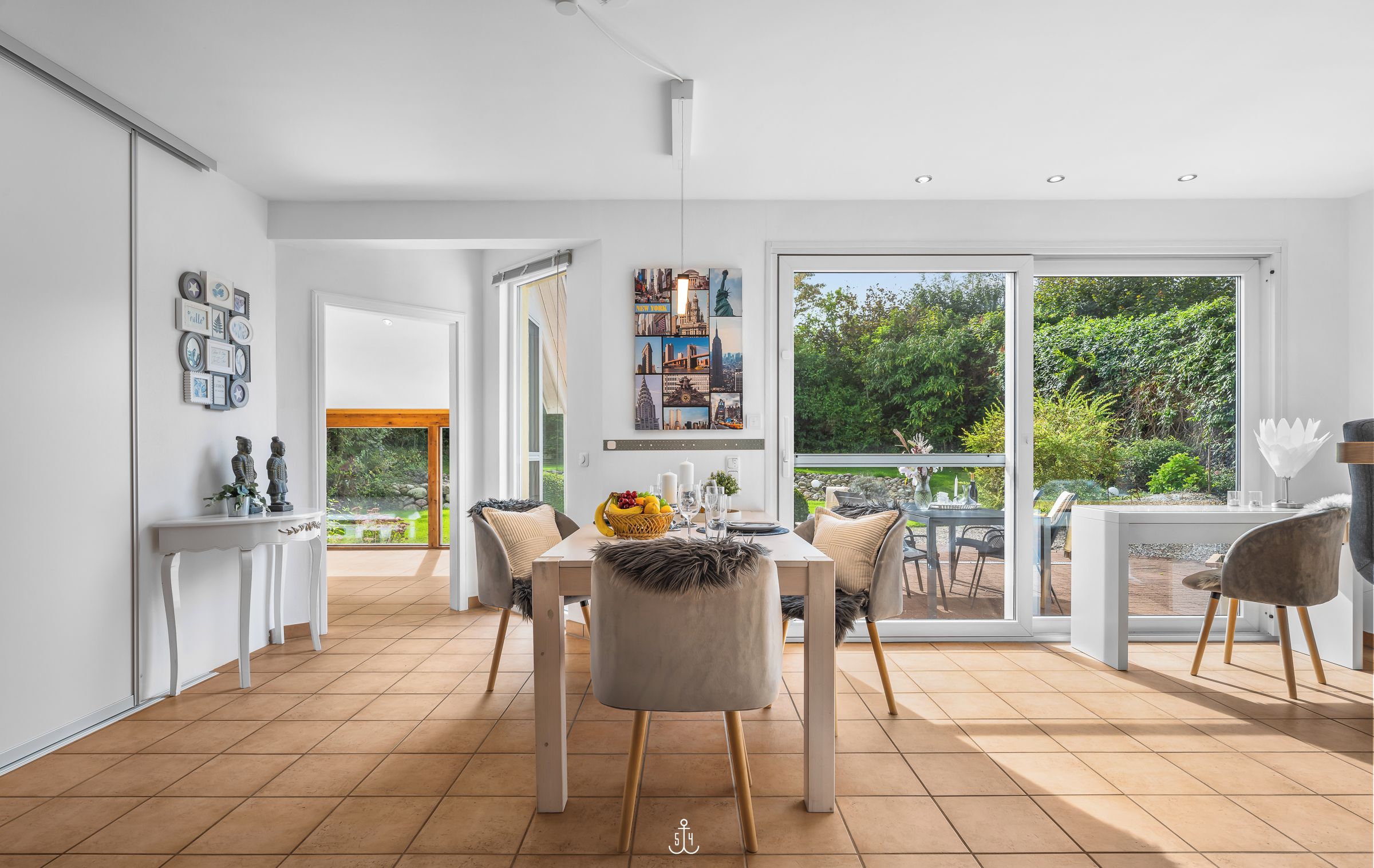 A spacious dining area with a large table, chairs, and a view of the garden through glass doors.
