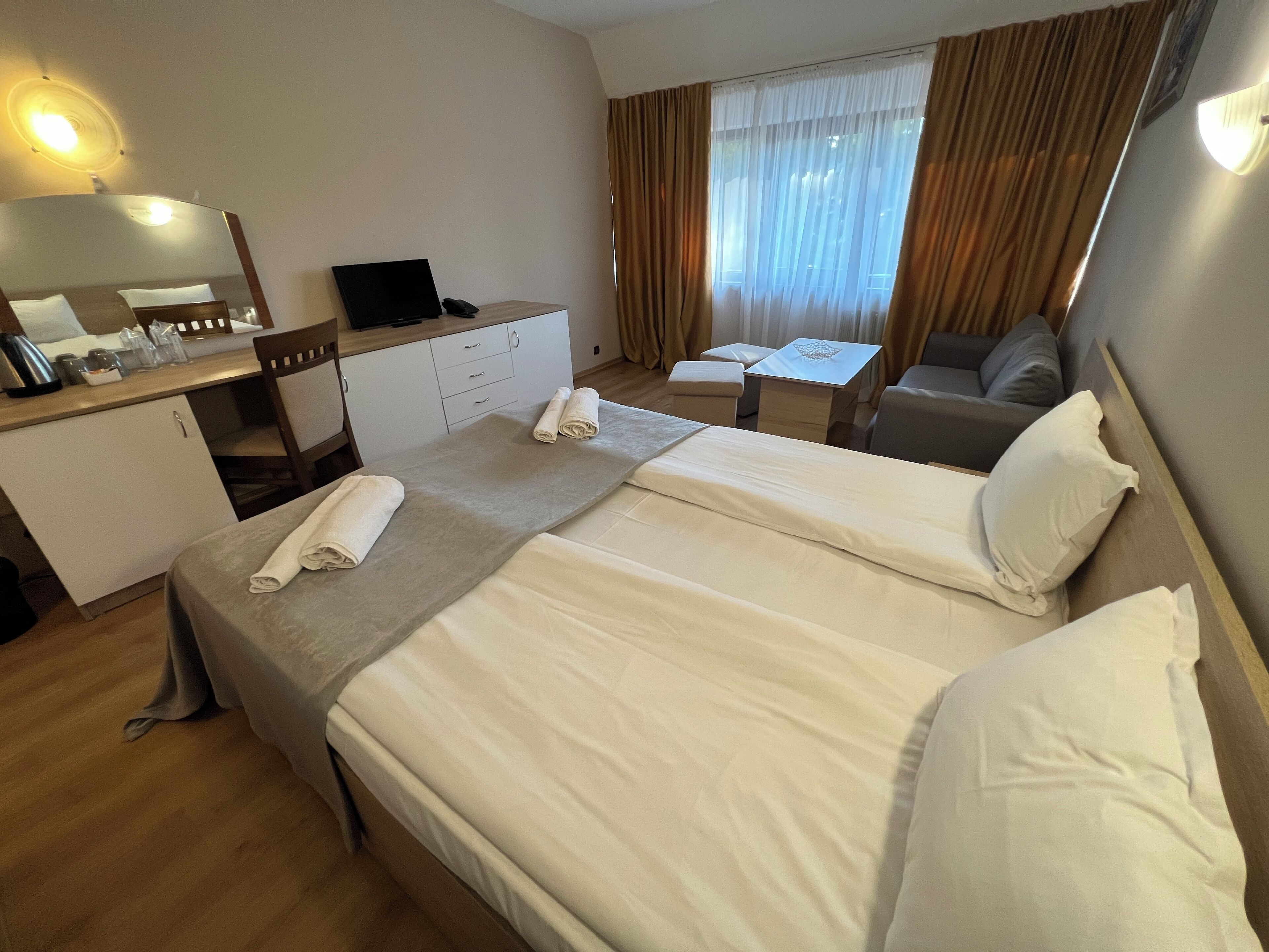 Een hotelkamer met een bed, een bureau, een stoel, een klein tafeltje en een spiegel.