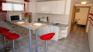Une cuisine moderne avec des meubles blancs, un four à micro-ondes, un évier et deux tabourets de bar rouges.