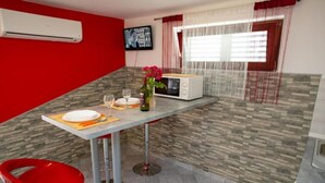 Une cuisine compacte équipée d’un four à micro-ondes, d’une petite table à manger et d’une chaise rouge.