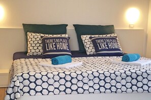 Ein Bett mit einem gemusterten Bettbezug und zwei passende Kissen mit der Aufschrift "There's no place like home."