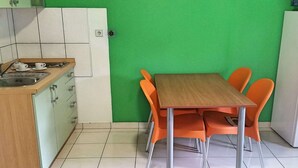 A small kitchen with a sink, cabinets, and a table with orange chairs.