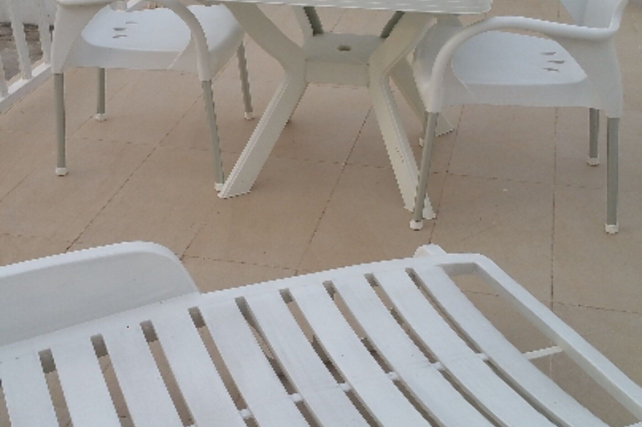 A white outdoor seating area with a table and chairs.