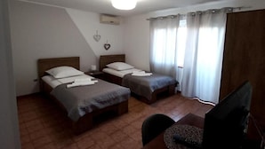 Un dormitorio con dos camas individuales, un escritorio con ordenador y una ventana con cortinas.