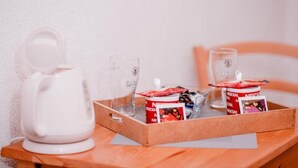 Un plateau avec une cafetière blanche, deux verres et deux boîtes de café instantané Nescafé, le tout posé sur une table en bois.