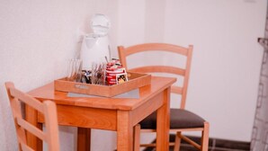 Une petite table en bois sur laquelle se trouve un plateau contenant une machine à café, une boîte de capsules de café Nespresso et un verre.