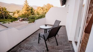 Un balcon avec une table et des chaises, une vue sur le paysage environnant et une porte donnant sur l’intérieur.