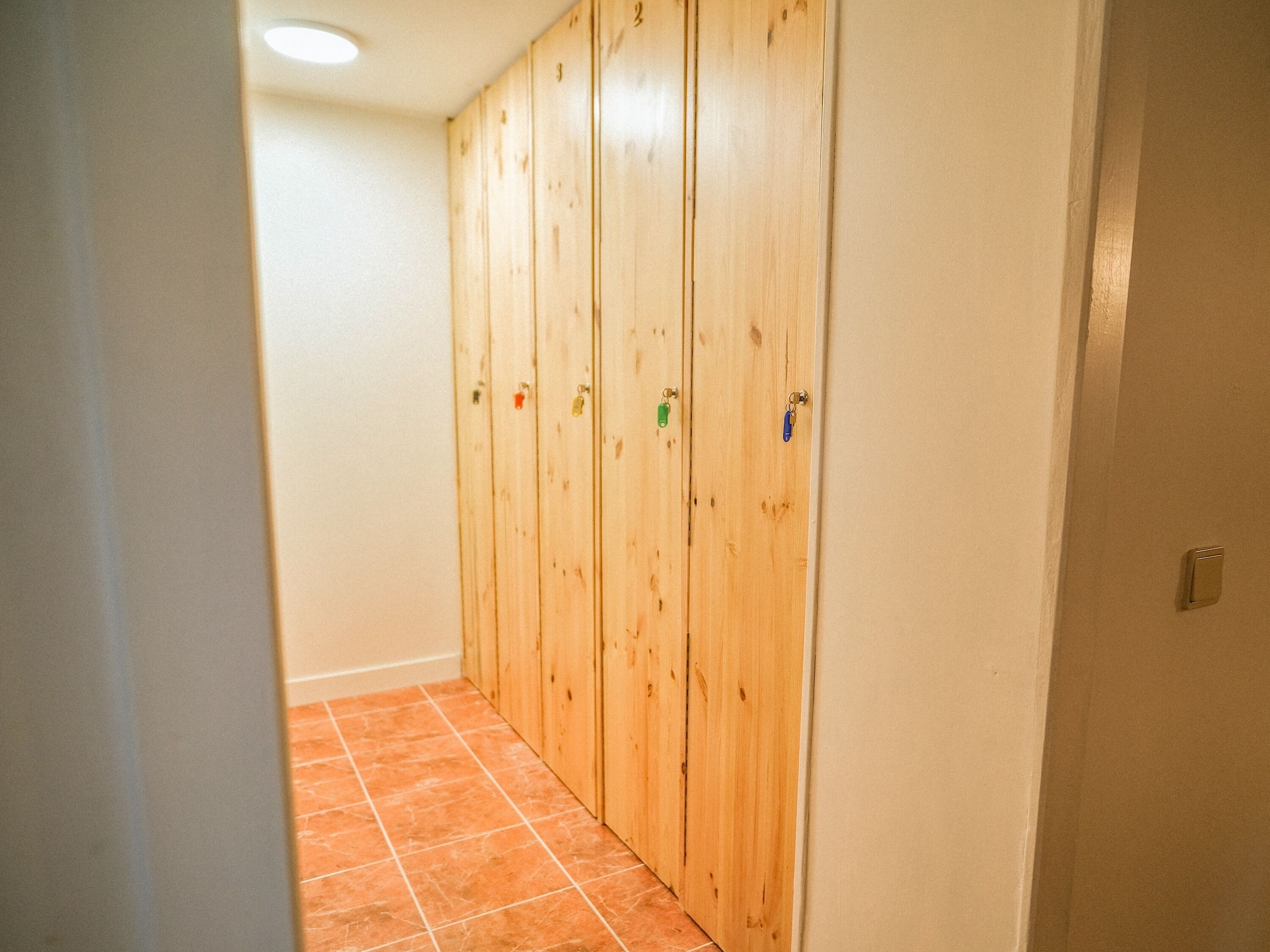 A hallway with wooden doors and orange-tiled flooring.