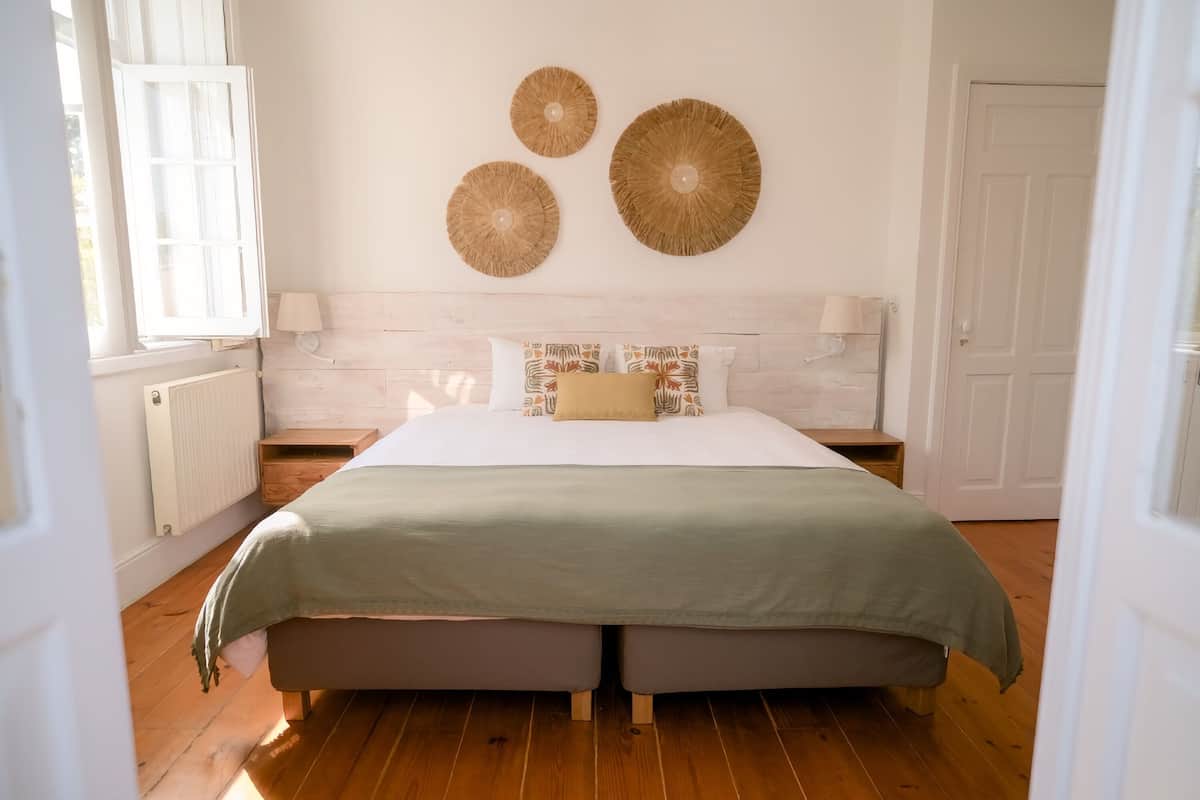 A bedroom with a bed, wooden floor, and wall decor.