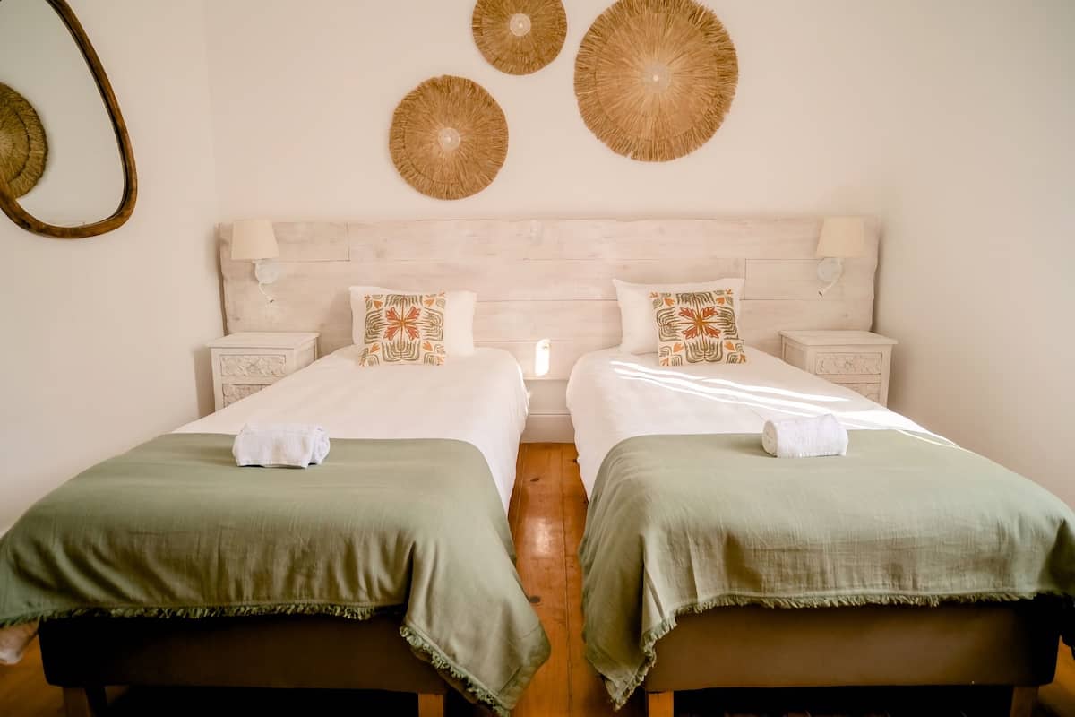 A double bed with two nightstands, a wooden headboard, and decorative wall art.