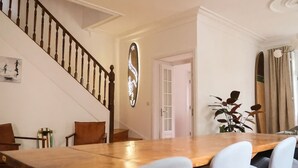 A dining area with a wooden table and chairs, a staircase with wooden balusters, and a chandelier. - Porto Surf Lodge (Porto)
