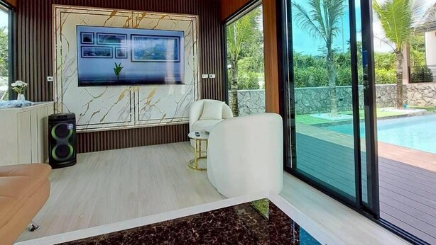 Un soggiorno moderno con una grande televisione, posti a sedere confortevoli e vista su una piscina.