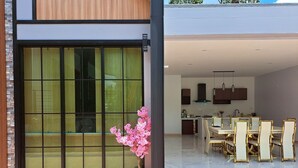 Una casa moderna con un'ampia porta scorrevole in vetro, una zona pranzo con pavimento in marmo e una cucina con mobili scuri.