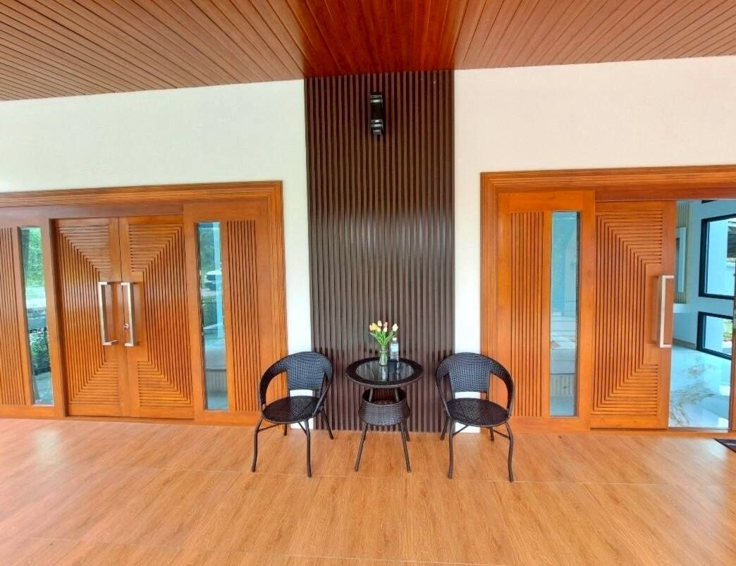 A spacious room with a wooden floor, a central table with chairs, and a decorative wall panel.