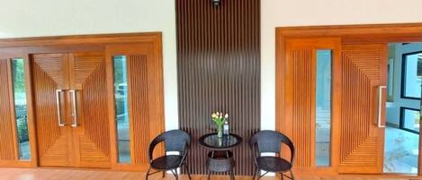 A spacious room with a wooden floor, a central table with chairs, and a decorative wall panel.