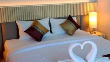 Ein Hotelzimmer mit einem ordentlich bezogenem Bett, zwei Kissen, einem Kopfteil, einer Wandlampe und zwei gerahmten Blumenbildern.