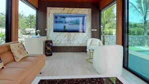 Un soggiorno moderno con soffitto in legno, ampie finestre, camino in marmo e televisore a schermo piatto.