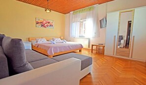 A bedroom with a bed, a sofa, a television, and a wardrobe.