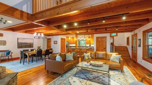 A spacious living room with wooden beams, a dining area, and a kitchen with wooden cabinets.