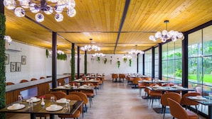 Un vaste espace dédié à la salle à manger, doté d’un plafond en bois, de grandes fenêtres et d’un éclairage moderne.