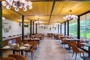 A spacious dining area with wooden ceiling, large windows, and modern lighting fixtures. - Raha Farms Pet friendly Resort ELIVAAS (Faridabad)