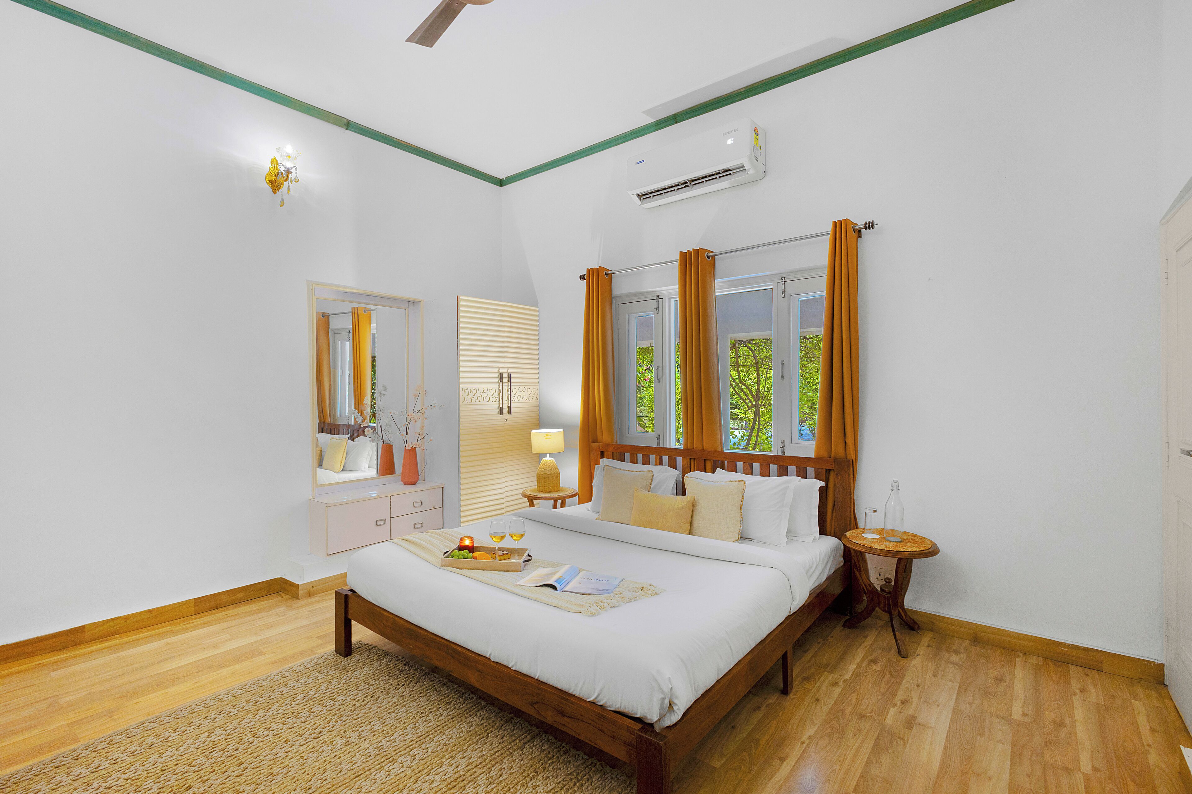 A bedroom with a bed, bedside table, mirror, and window with curtains.