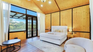 Une chambre à coucher avec un grand lit, une table de chevet, une chaise et une vue sur l’extérieur grâce à une porte coulissante.