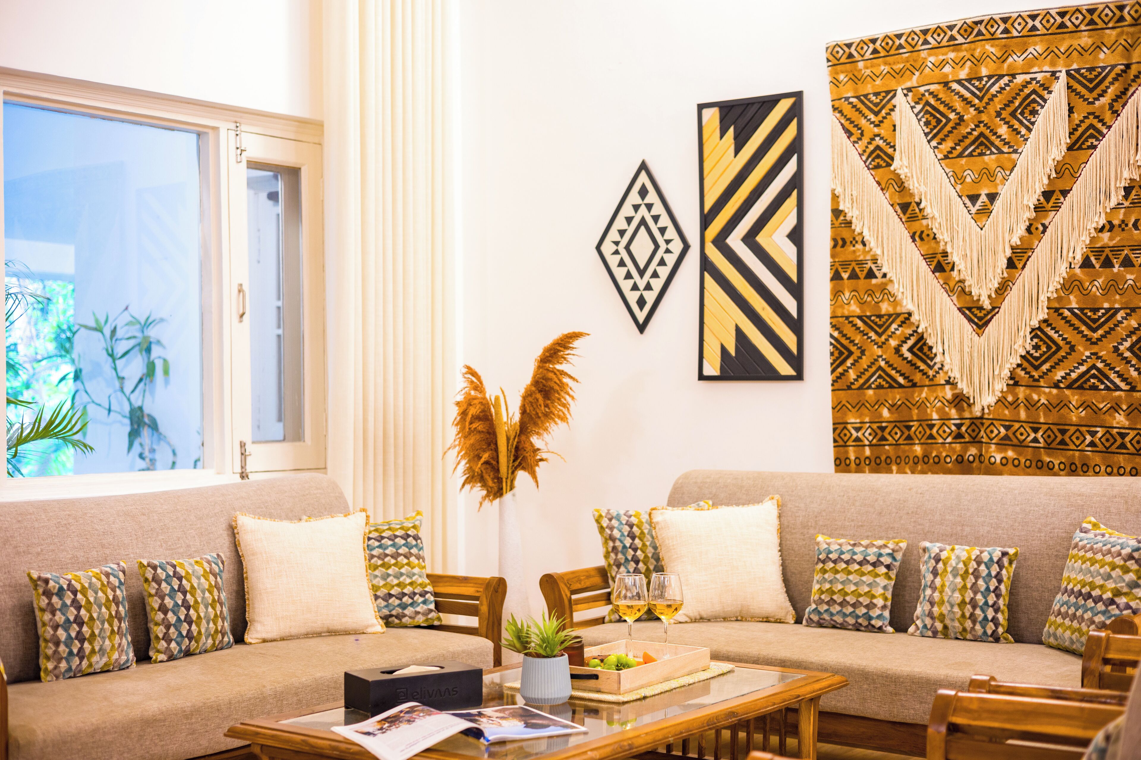 Un soggiorno moderno con un divano beige, cuscini decorati, un tavolino da caffè con una rivista e elementi decorativi alle pareti.