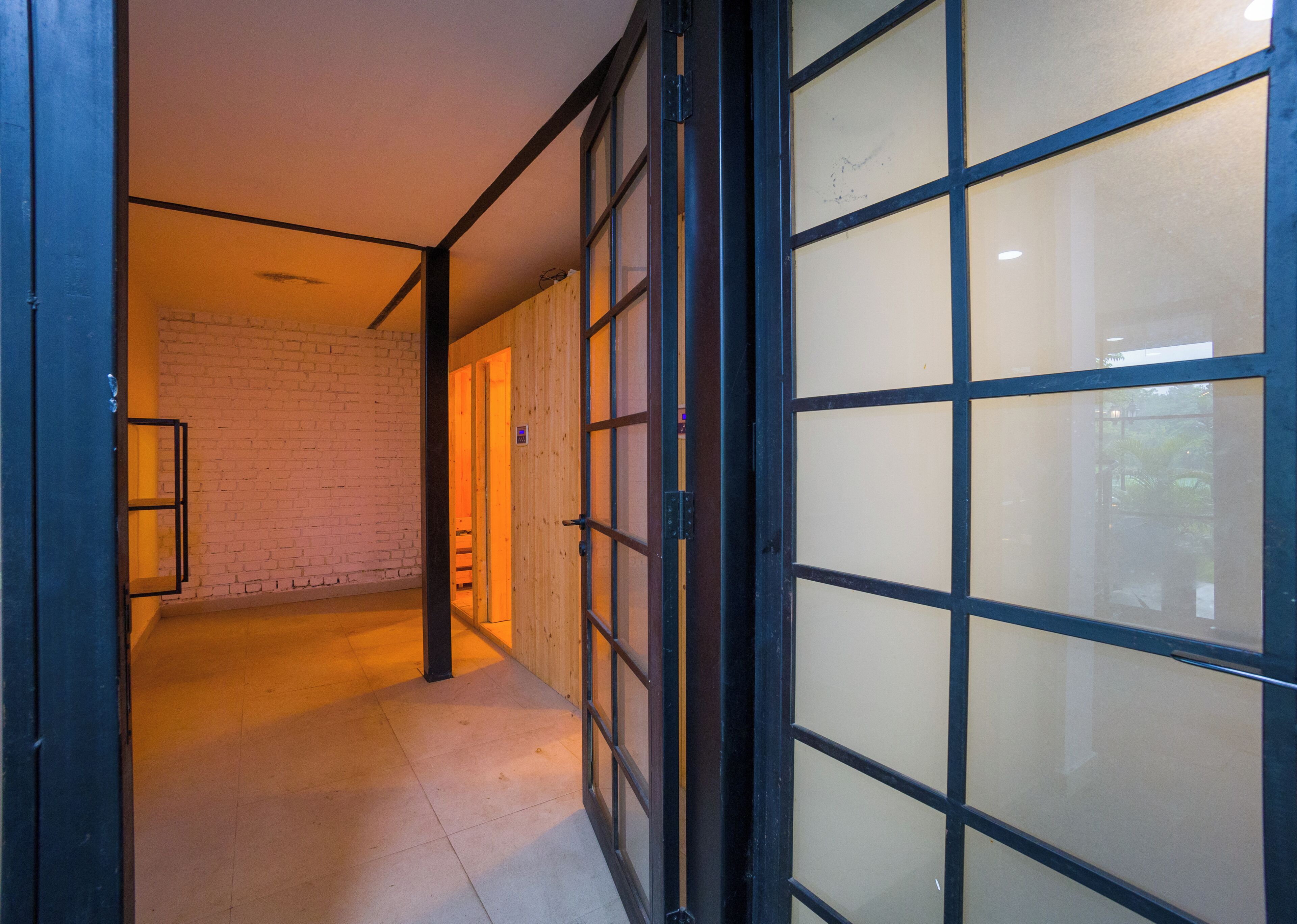 A hallway with a wooden door, a brick wall, and a tiled floor.