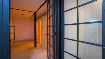A hallway with a wooden door, a brick wall, and a tiled floor.