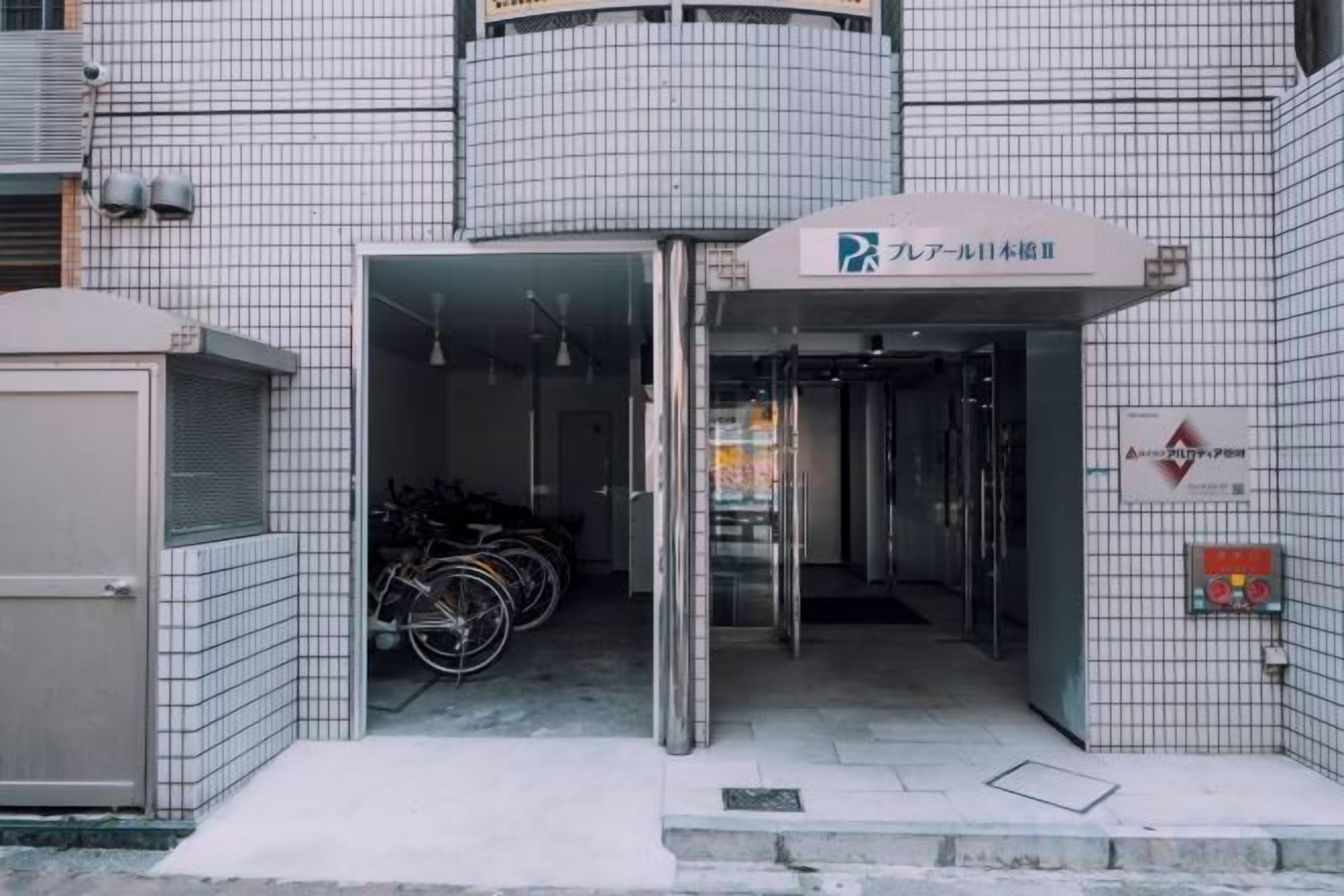 A building entrance with a bicycle parking area and a sign indicating a parking facility.