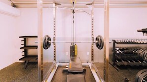 A gym with a squat rack, bench press, and dumbbells. - Minimalist Loft 5: Namba Compact Studio & 24/7 Gym (Osaka)