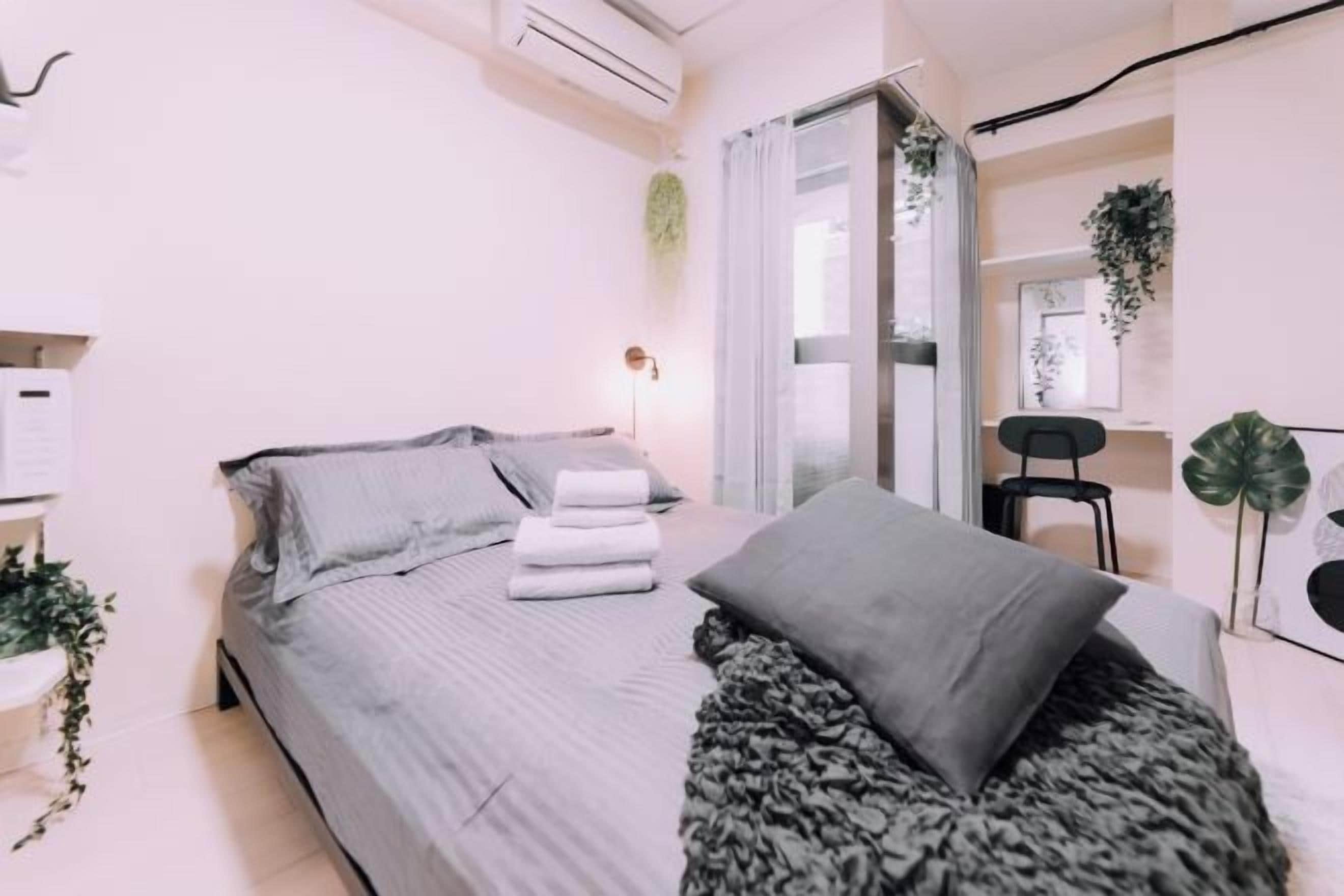 A modern bedroom with a bed, a bedside table, a chair, and a window with curtains.