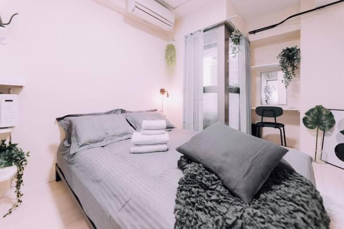 A modern bedroom with a bed, a bedside table, a chair, and a window with curtains.