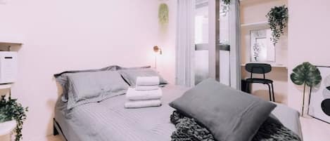 A modern bedroom with a bed, a bedside table, a chair, and a window with curtains.