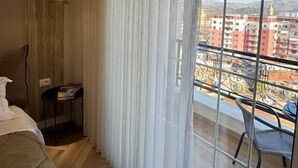 A bedroom with a large window, a bed, a small table, and a chair. - Downtown Shkodra Apartment (Shkodër)