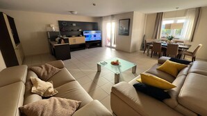 Una sala de estar con un sofá, una mesa de centro y un televisor al fondo.