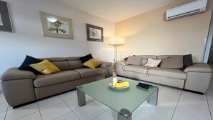 Una sala de estar moderna con dos sofás, una mesa de centro de vidrio y una lámpara de pie.
