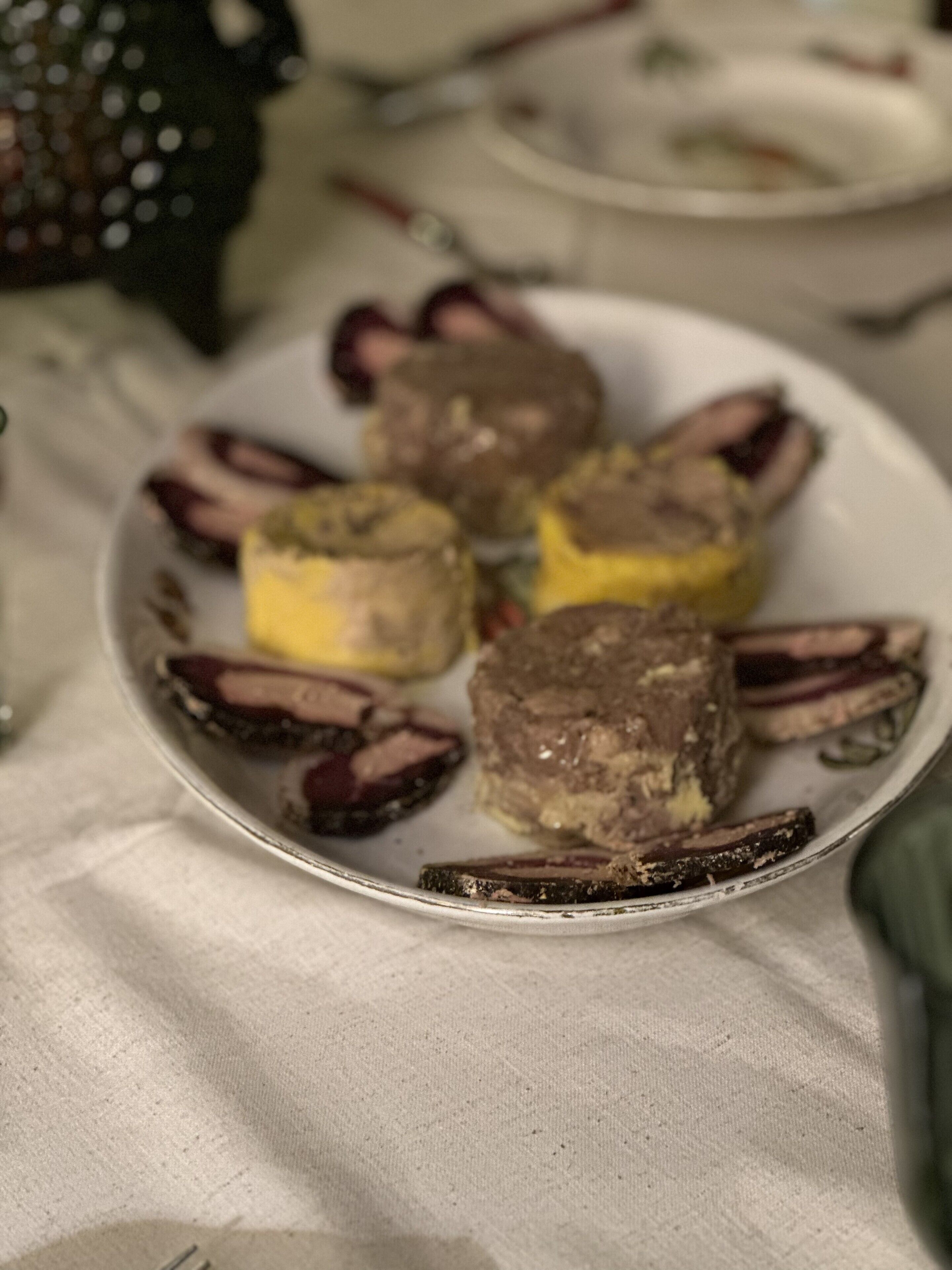 Ein Teller mit verschiedenen Speisen, darunter offenbar Fleisch und Gemüse, auf einer Tischdecke.