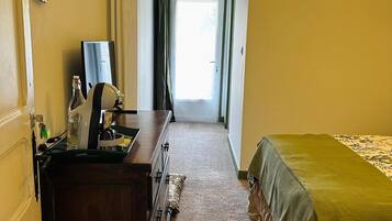 Una camera d'albergo con un letto, una cassettiera, uno specchio e una finestra con tende.