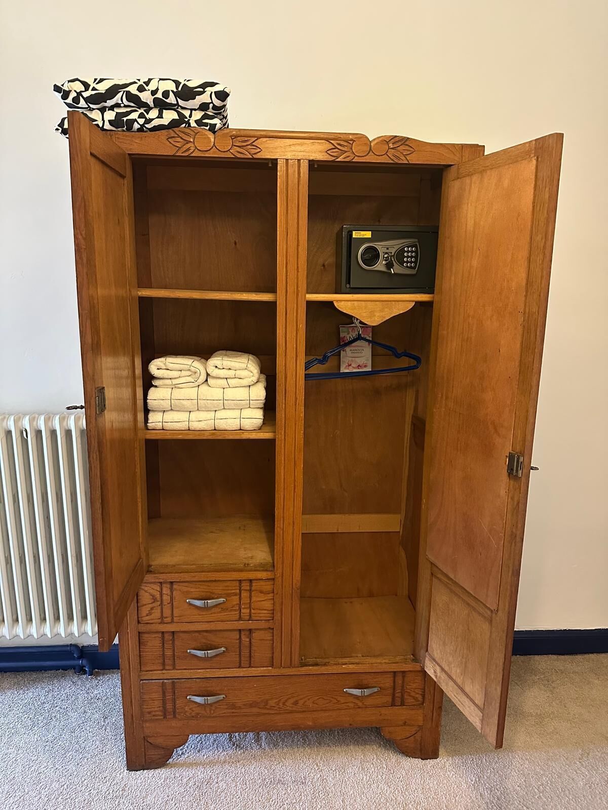 Un armario de madera con múltiples repisas, una radio y una percha para colgar ropa.
