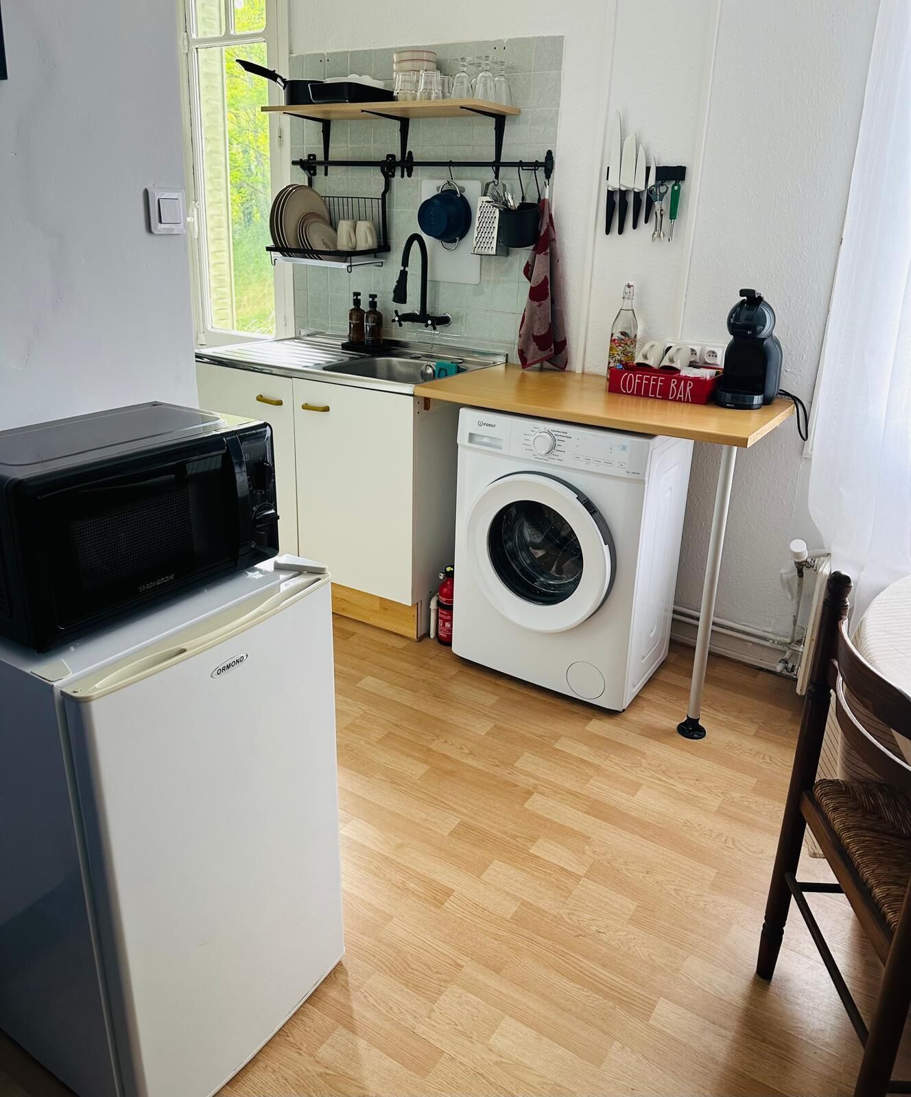 Une cuisine compacte équipée d’un four à micro-ondes, d’un lave-linge et d’un coin café.