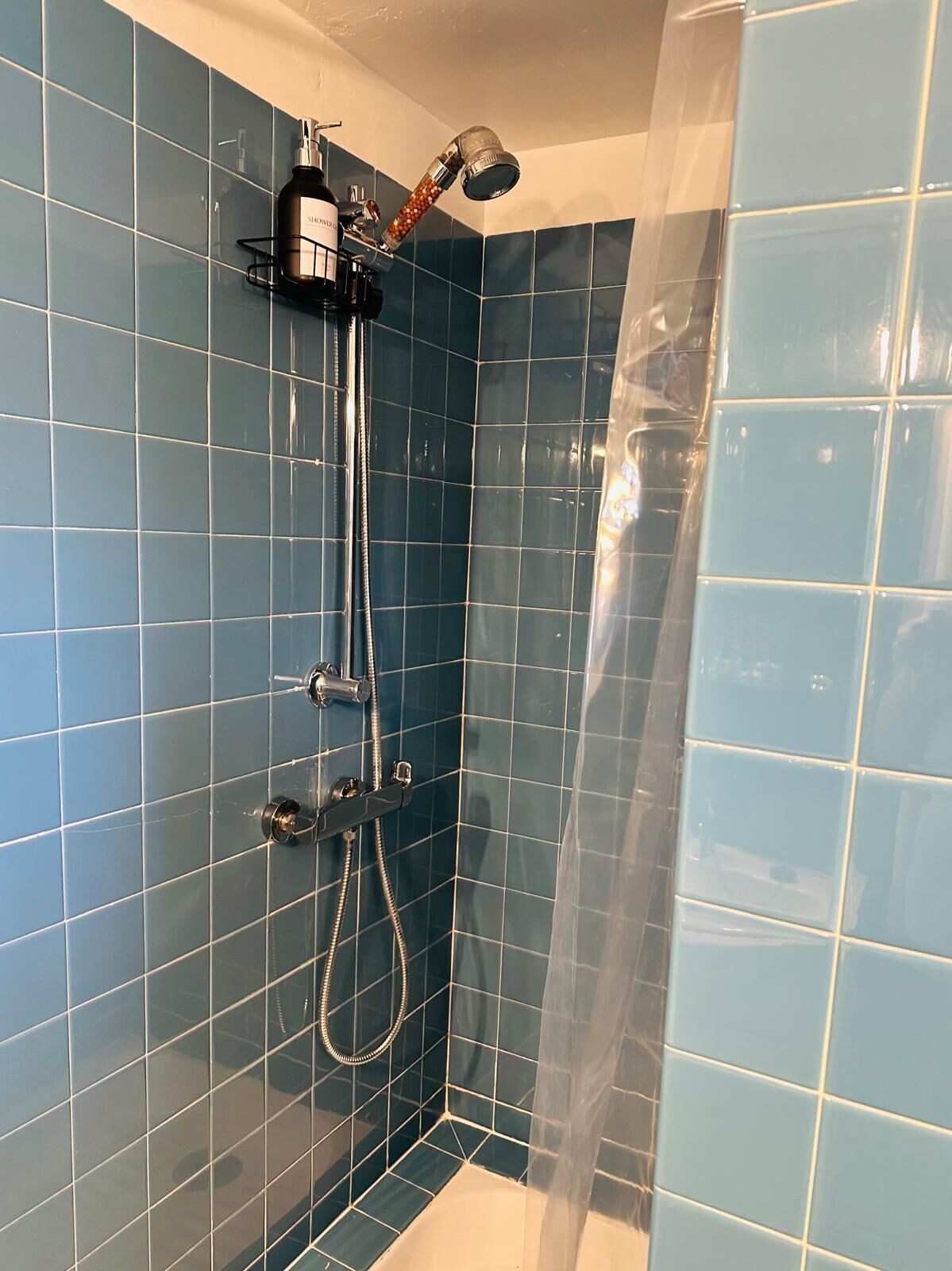 A shower with a handheld showerhead and a handheld massager.