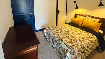 Un dormitorio con cama, cómoda, puerta y lámpara.