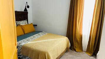 A bedroom with a bed, a hanging lamp, and curtains.